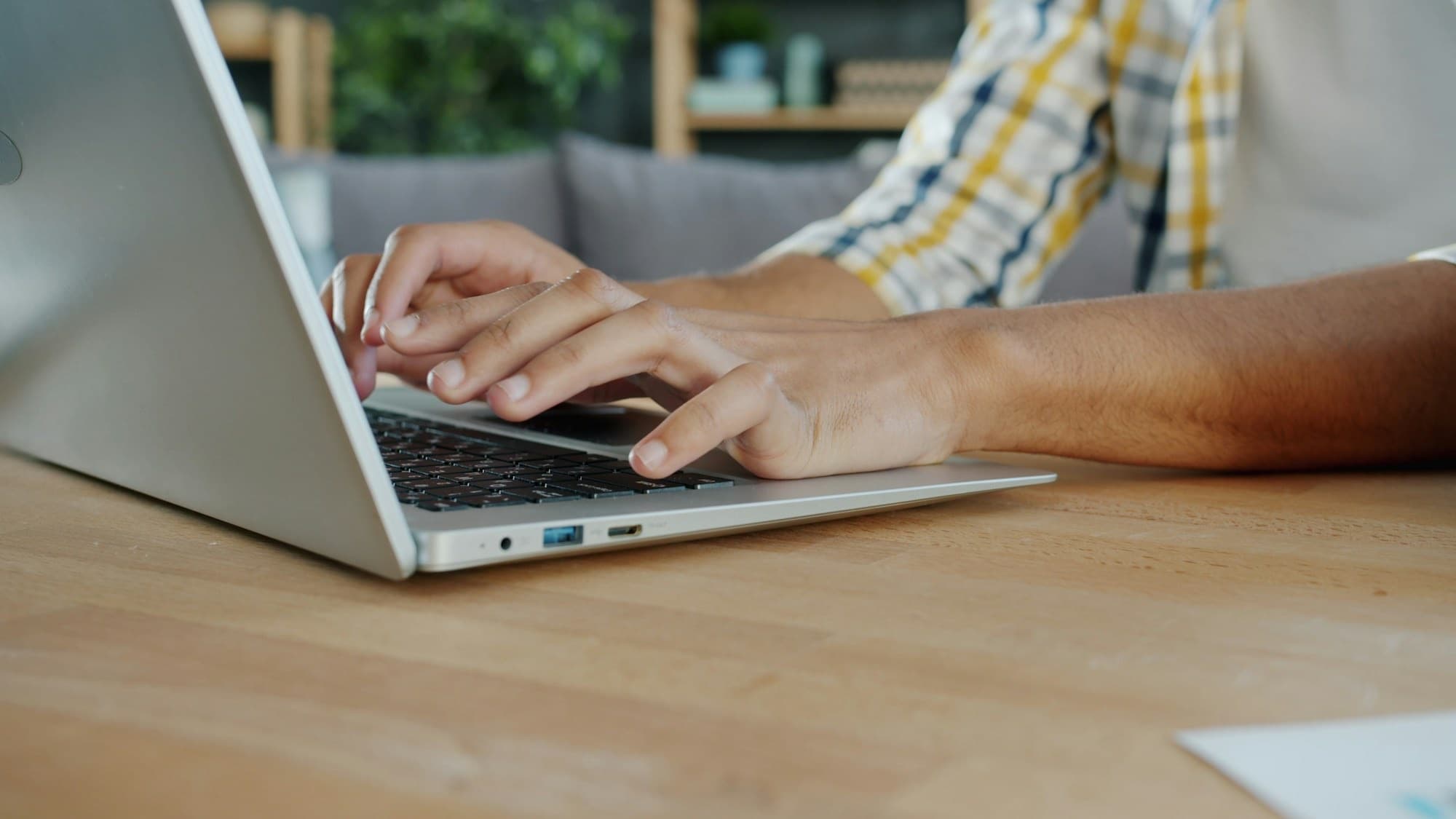Händer som skriver på en laptop vid ett köksbord